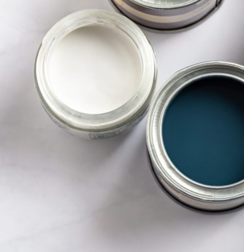 Tiny sample paint cans during house renovation, process of choosing paint for the walls, different green and beige colors, color charts on background